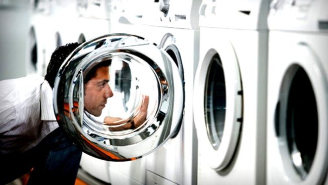 мужчина смотрит в стиральную машину, установка самостоятельная
